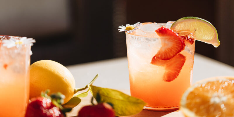 garnished glass of wine spritzer with strawberries and lemon