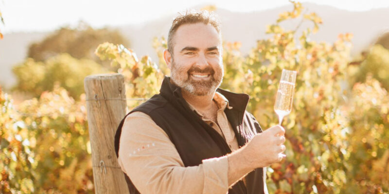 ONEHOPE Wine Founder Jake enjoying the benefits of wine club while drinking sparkling wine in the vineyard