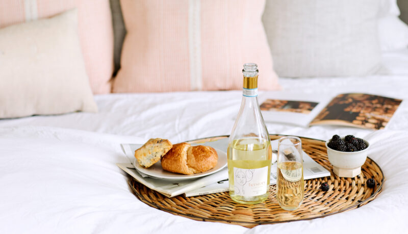 Mother's day brunch spread in bed featuring onehope herstory wine and two pastries