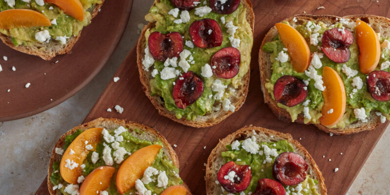 Apricot & Cherry Avocado Toasts on wooden cutting board