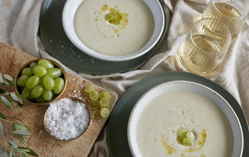 Plated White Gazpacho with wood board that has grapes on it