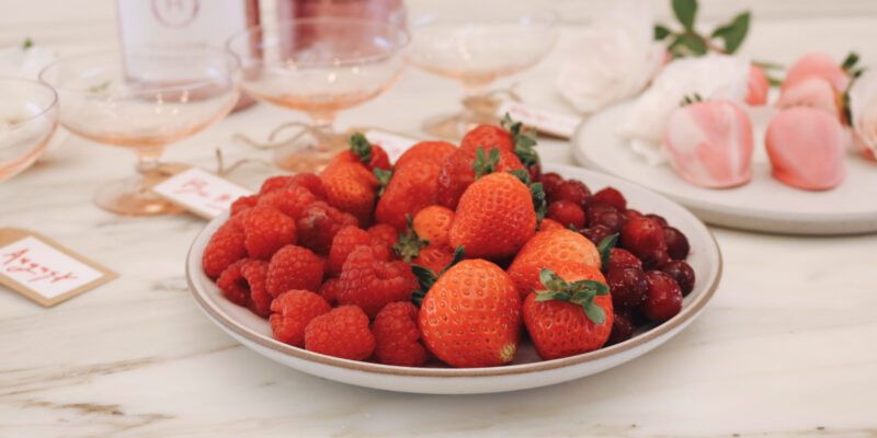 Fresh strawberries, raspberries, and cranberries on a plate, perfect for pairing with ONEHOPE Sparkling Rosé for a Galentine’s Night In celebration.